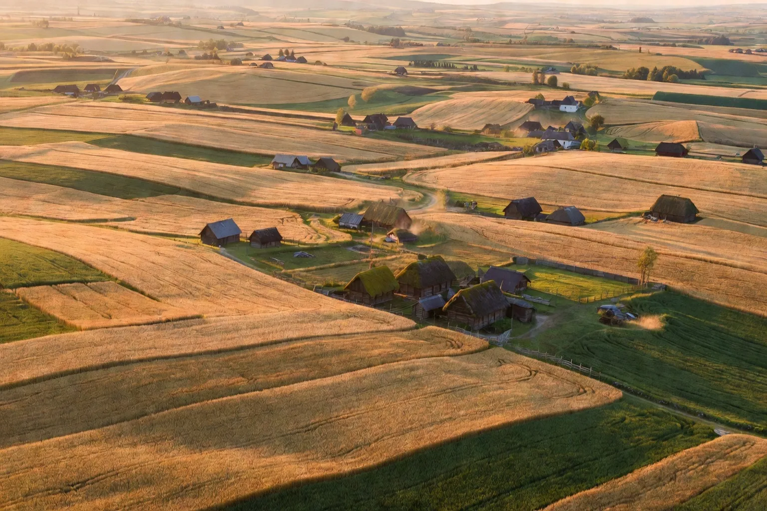 Paysage céréalier européen avec parcelles cultivées en damier et silos coopératifs en arrière-plan